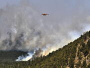 A firefighting plane flies over a plume of smoke near Las Vegas, N.M. on Wednesday, May 4, 2022. The fire has torched 250 square miles (647 square kilometers) over the last several weeks.