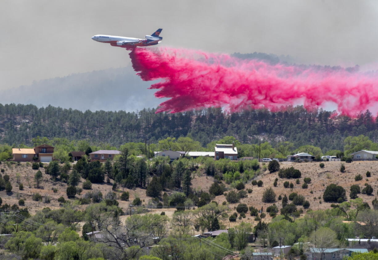 A slurry bomber dumps the fire retardant between the Calf Canyon/Hermit Peak Fire and homes on the westside of Las Vegas, N.M., Tuesday, May 3, 2022. Several types of aircraft joined the fight to keep the fire away for the Northern New Mexico town.