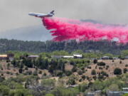 A slurry bomber dumps the fire retardant between the Calf Canyon/Hermit Peak Fire and homes on the westside of Las Vegas, N.M., Tuesday, May 3, 2022. Several types of aircraft joined the fight to keep the fire away for the Northern New Mexico town.