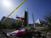 FILE - Flowers sit outside crime scene tape at Geneva Presbyterian Church on May 17, 2022, in Laguna Woods, Calif., where a shooting at the church on Sunday left one dead and five injured. Officials in California's Orange County are still trying to determine why a gunman opened fire in the church.