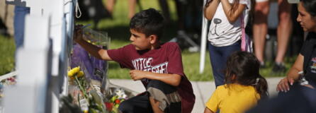 A child writes a message on a cross at a memorial site for the victims killed in this week's elementary school shooting in Uvalde, Texas, Thursday, May 26, 2022.