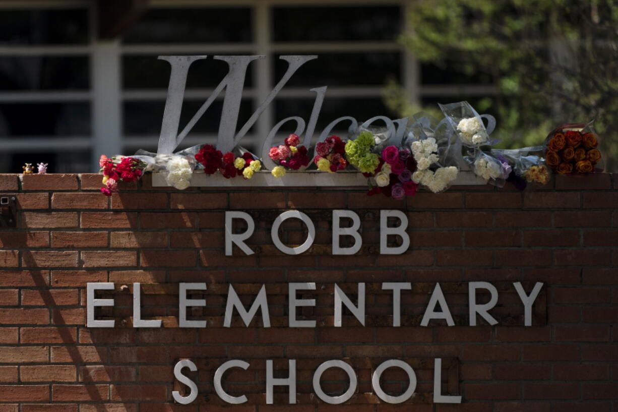 Flowers are placed around a welcome sign outside Robb Elementary School in Uvalde, Texas, Wednesday, May 25, 2022, to honor the victims killed in Tuesday's shooting at the school. Desperation turned to heart-wrenching sorrow for families of grade schoolers killed after an 18-year-old gunman barricaded himself in their Texas classroom and began shooting, killing several fourth-graders and their teachers. (AP Photo/Jae C.