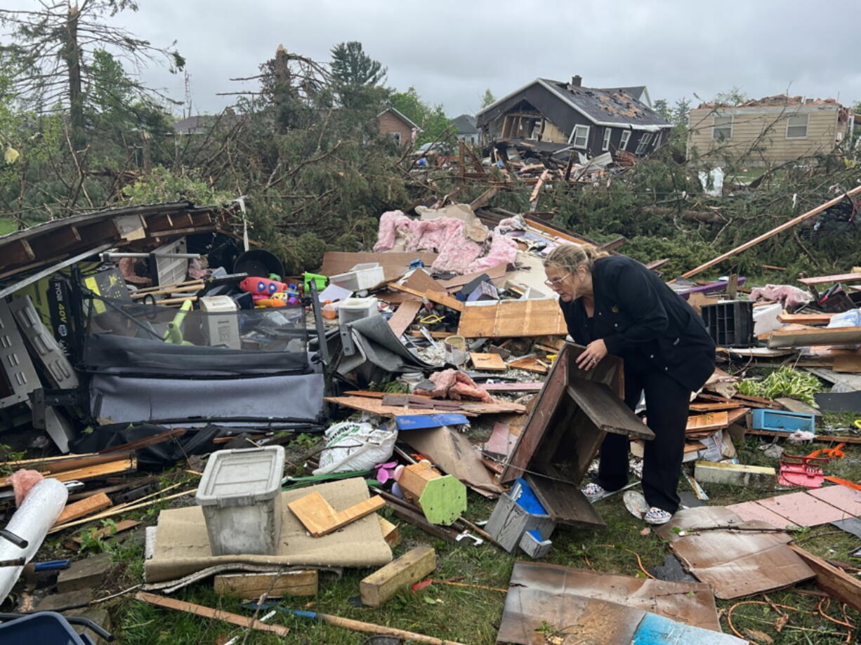 Theresa Haske sorts through debris from what was her garage after a tornado tore through Gaylord, Mich., Friday, May 20, 2022.