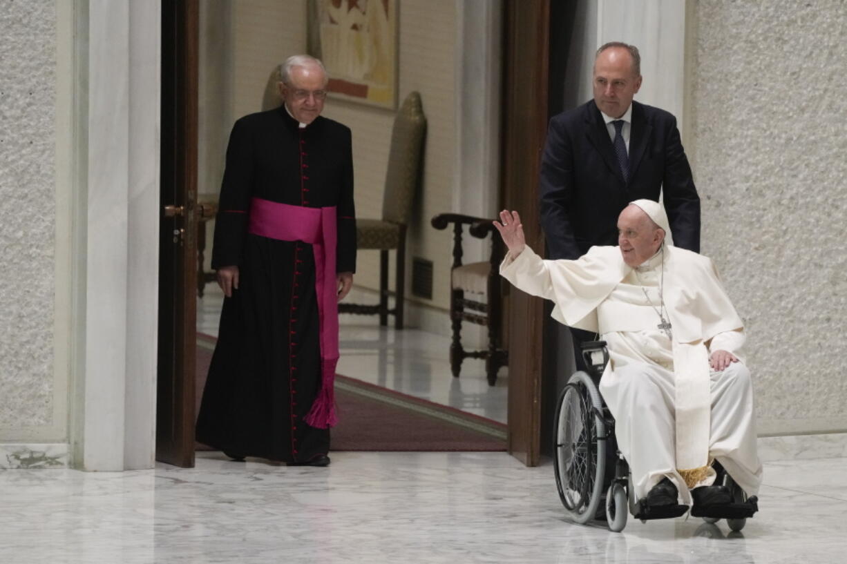 Pope Francis arrives in a wheel chair in the Paul VI hall to attend an audience with pilgrims from central Italy at the Vatican, Saturday, May 14, 2022.