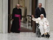 Pope Francis arrives in a wheel chair in the Paul VI hall to attend an audience with pilgrims from central Italy at the Vatican, Saturday, May 14, 2022.