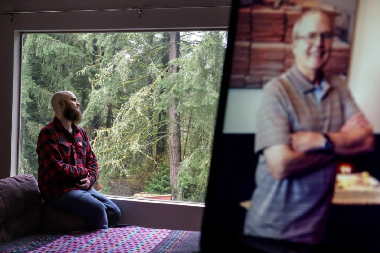 Nathan Lambrecht is photographed next to a picture of his father, Doug Lambrecht, at his apartment in Woodinville, Wash., Monday, March 21, 2022. The 71-year-old retired physician was among the first of the nearly 1 million Americans to die from COVID-19. "I'm afraid that as the numbers get bigger, people are going to care less and less," Nathan said.