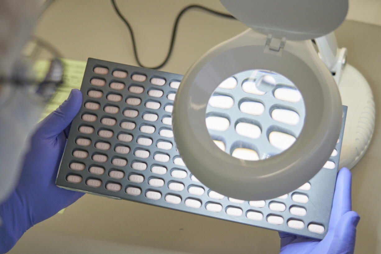 FILE - In this photo provided by Pfizer, a lab technician visually inspects COVID-19 Paxlovid tablet samples in Freiburg, Germany in December 2021. As more doctors prescribe Pfizer's powerful COVID-19 pill, new questions are emerging about its performance, including why a small number of patients appear to relapse after taking the drug.