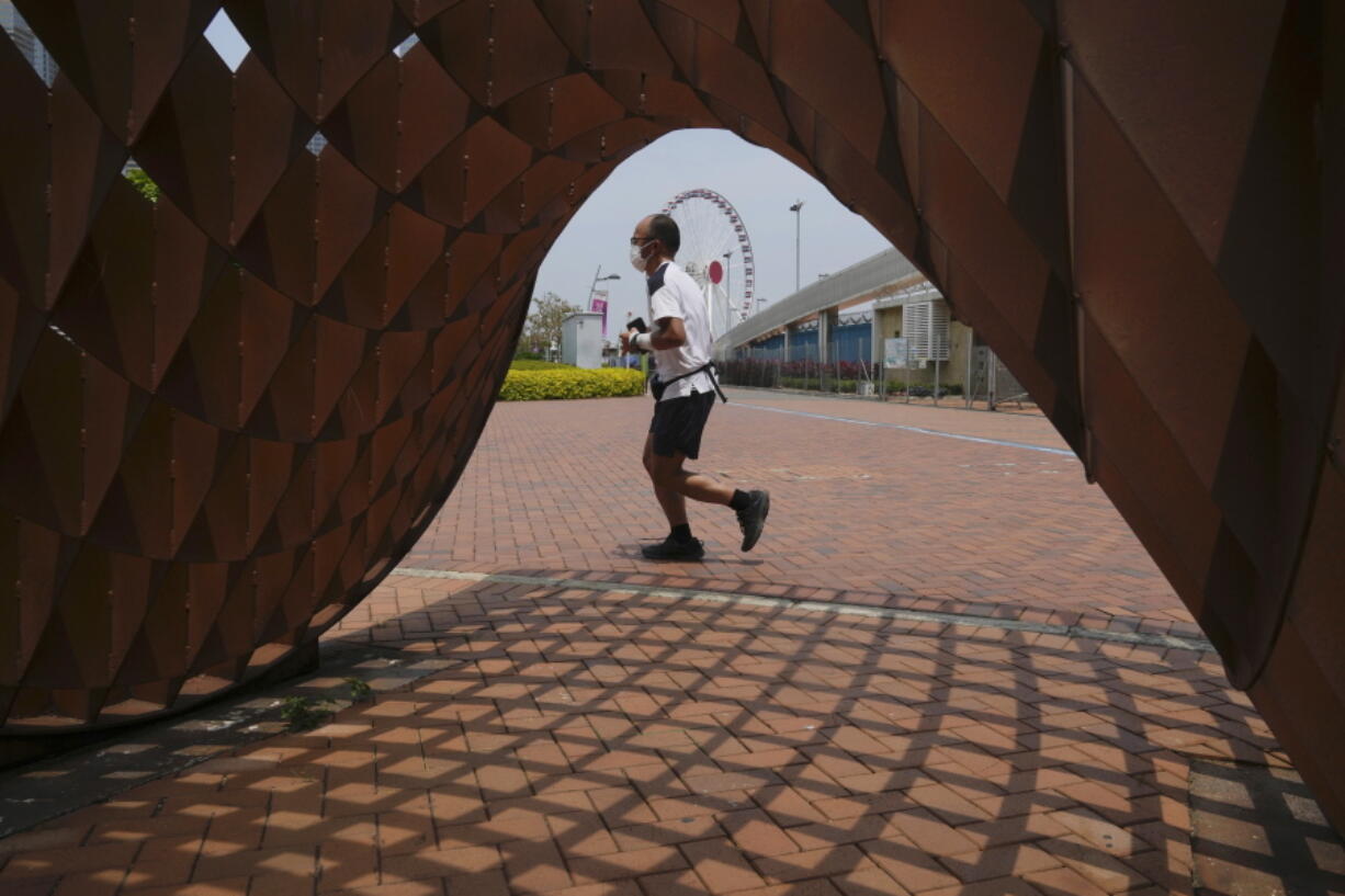 A man jogs in a park in Hong Kong, Thursday , May 5, 2022. Hong Kong on Thursday reopened beaches and pools in a relaxation of COVID-19 restrictions, while China's capital Beijing began easing quarantine rules for arrivals from overseas.