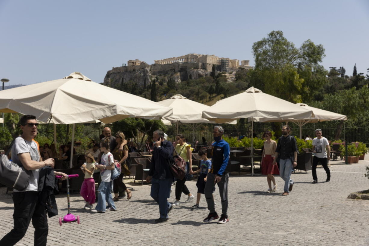 People make their way on a pedestrian street at the foot of the Acropolis hill, in Athens, on Sunday, May 1, 2022. Italy and Greece relaxed some COVID-19 restrictions on Sunday, in a sign that life was increasingly returning to normal before Europe's peak summer tourist season.