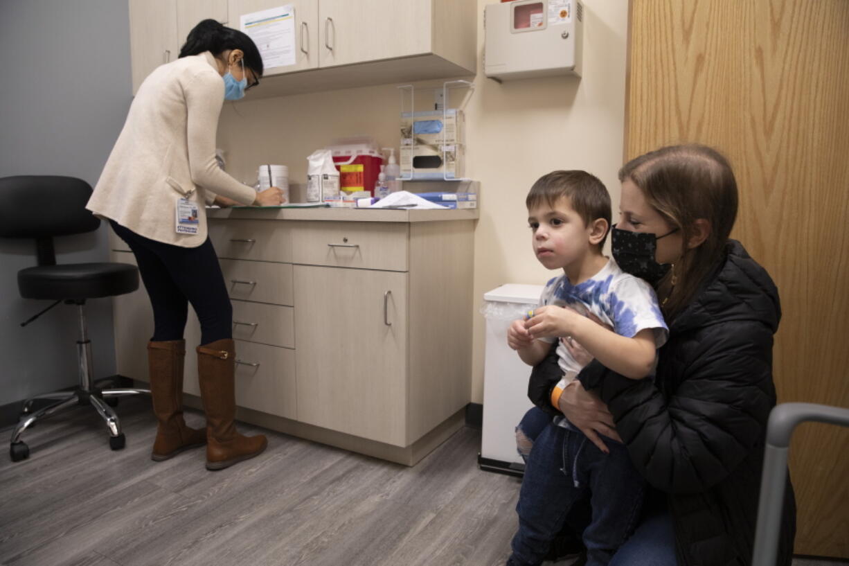 FILE - Ilana Diener holds her son, Hudson, 3, during an appointment for a Moderna COVID-19 vaccine trial in Commack, N.Y. on Nov. 30, 2021. Parents hoping to get their youngest children vaccinated against COVID-19 have some encouraging news. Pfizer said Monday, May 23, 2022, that three doses of its vaccines offers strong protection to those under 5. That news comes a month after Moderna said it would ask regulators to OK its two shot regimen for the youngest kids. (AP Photo/Emma H.