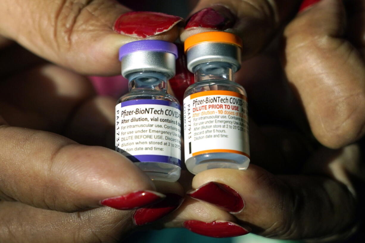 FILE - A nurse holds a vial of the Pfizer COVID-19 vaccine for children ages 5 to 11, right, and a vial of the vaccine for adults, which has a different colored label, at a vaccination station in Jackson, Miss., Tuesday, Feb. 8, 2022. (AP Photo/Rogelio V.