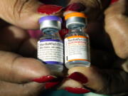 FILE - A nurse holds a vial of the Pfizer COVID-19 vaccine for children ages 5 to 11, right, and a vial of the vaccine for adults, which has a different colored label, at a vaccination station in Jackson, Miss., Tuesday, Feb. 8, 2022. (AP Photo/Rogelio V.