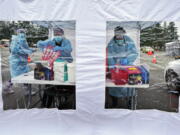 FILE - Workers at a drive-up COVID-19 testing clinic stand in a tent as they prepare PCR coronavirus tests, Jan. 4, 2022, in Puyallup, Wash., south of Seattle. Testing for COVID-19 has plummeted across the globe, dropping by 70 to 90% worldwide from the first to the second quarter of 2022, making it much tougher for scientists to track the course of the pandemic and spot new, worrisome viral mutants as they emerge and spread. (AP Photo/Ted S.