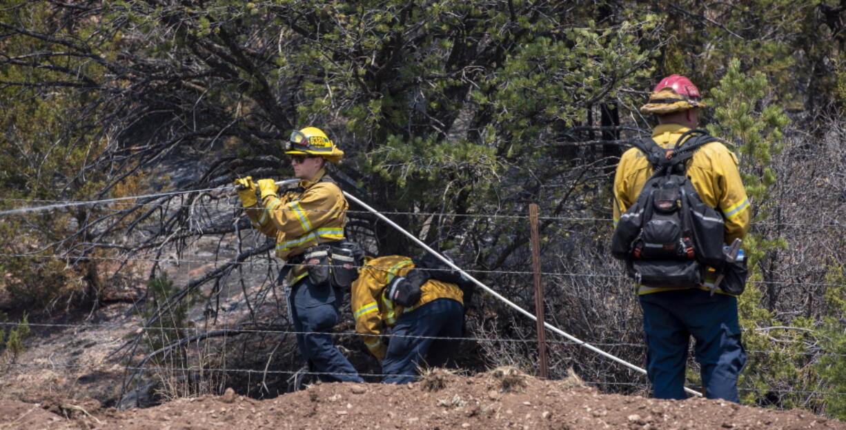 Jeff Franco, left, and other wildland firefighters from Apple Valley, Calif., mop up hot spots along NM 283 near Las Vegas, N.M., Thursday, May 5, 2022. Firefighters are trying to hold the Calf Canyon/Hermit Peak Fire at the road and not let it cross.