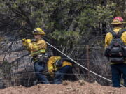 Jeff Franco, left, and other wildland firefighters from Apple Valley, Calif., mop up hot spots along NM 283 near Las Vegas, N.M., Thursday, May 5, 2022. Firefighters are trying to hold the Calf Canyon/Hermit Peak Fire at the road and not let it cross.