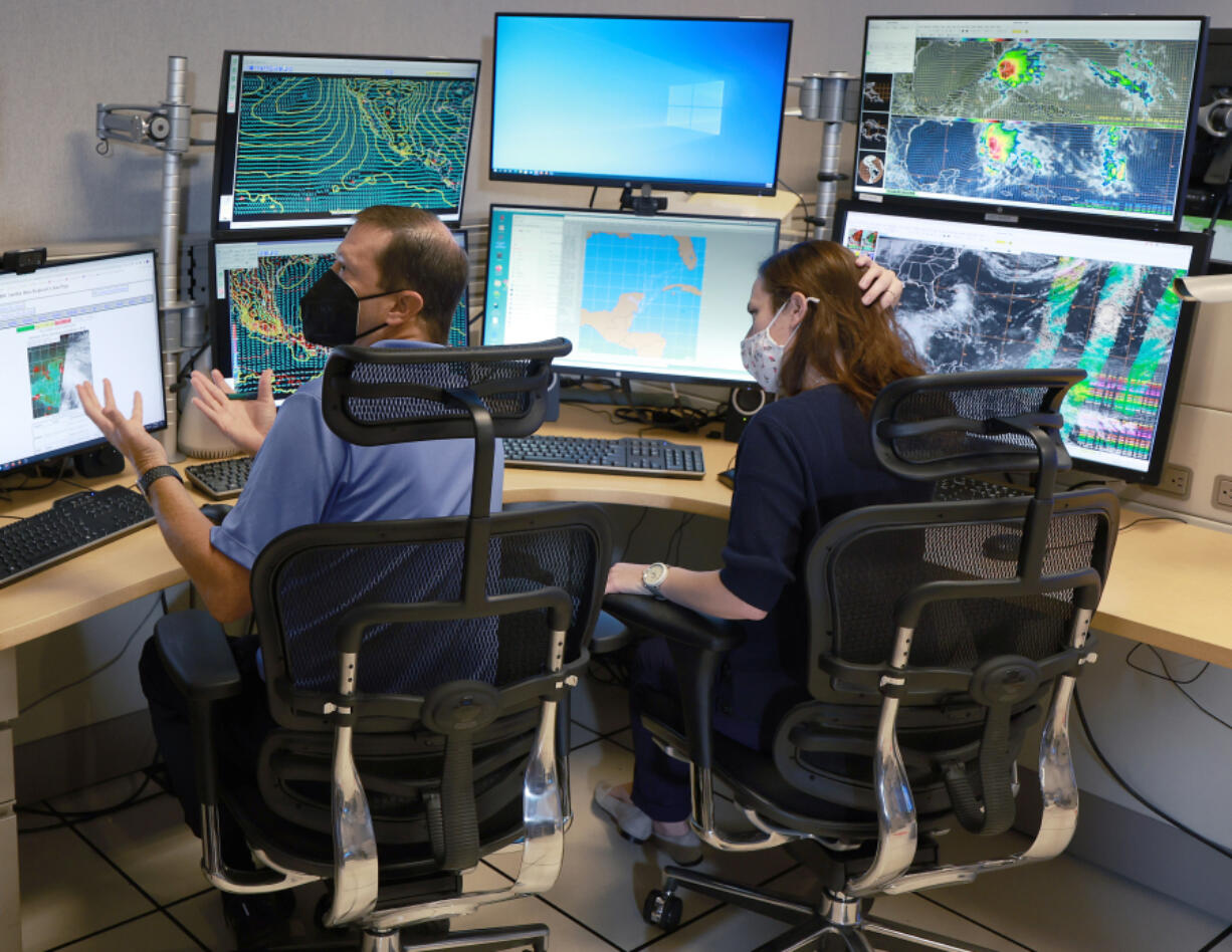 Daniel Brown, left, senior hurricane specialist, and Lisa Bucci, hurricane research scientist, track the progress of what was once Hurricane Agatha at the National Hurricane Center on Wednesday, June 1, 2022, in Miami.