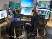 Daniel Brown, left, senior hurricane specialist, and Lisa Bucci, hurricane research scientist, track the progress of what was once Hurricane Agatha at the National Hurricane Center on Wednesday, June 1, 2022, in Miami.