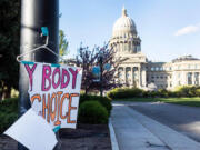 In this photo from May 3, 2022, a sign is taped to a hanger taped to a streetlight in front of the Idaho Capitol. (Sarah A.