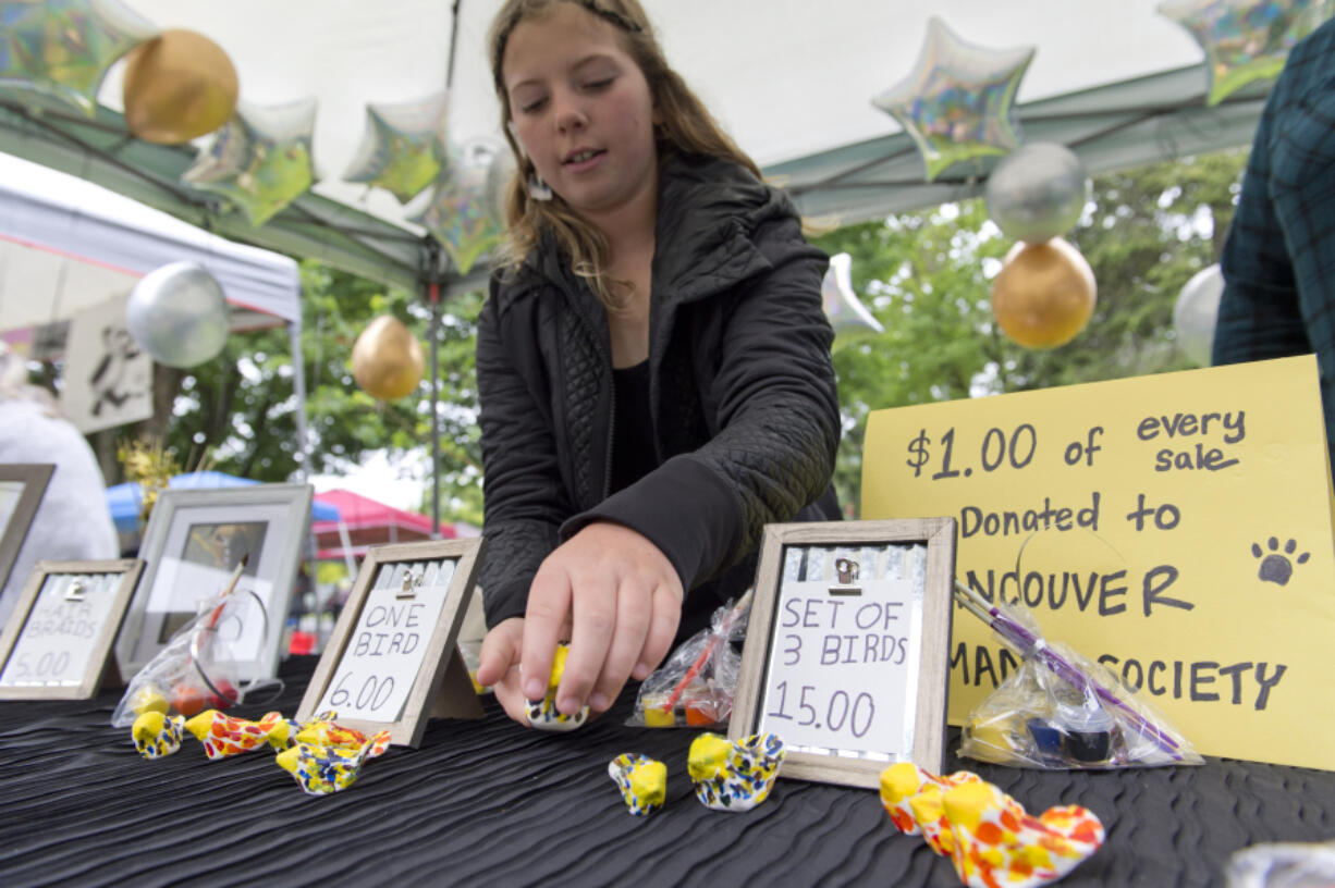 Young entrepreneur Lucy Hackett, 11, along with her mentor Casey Anderson, shows her painted birds and braiding skills at her business, Lucy's Lucky Birds and Braids, on Saturday at Esther Short Park.