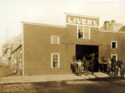 John Crass (in white shirt) stands near a helper, each holding two horses at a livery stable at 214 West Fourth St. in Vancouver. Besides horse and buggy rentals, livery stables were often a sort of community center offering after-hours entertainment from bawdy performances to pugilistic combat. During the day, they proved a reliable source for county gossip and rumors.