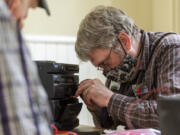 Repair Clark County volunteer Ken Olsen examines the tape deck of a stereo Wednesday at the Artillery Barracks at the For Vancouver National Historic Site in June.