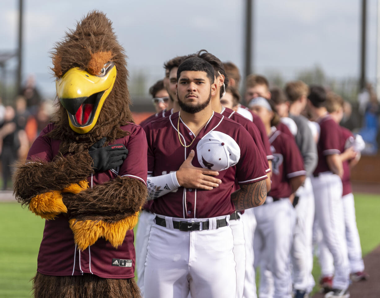 Rally the Raptor, left, and Ridgefield Raptors players stand for the national anthem Tuesday, June 14, 2022, during a Raptors game against the Edmonton Riverhawks at the Ridgefield Outdoor Recreation Complex.