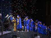 Graduates cross the stage to receive their diplomas as confetti falls Thursday at the Clark College commencement ceremony.