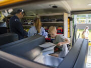 Quillian Moro, right, 7, checks out books while Camas School District Superintendent John Anzalone, left, shows Meridian Moro, center, 9, other available books Wednesday when the district's Book MoBus stopped at Helen Baller Elementary School.