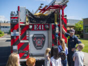 Camas-Washougal Fire Department firefighter Trevor Guay shows off a fire truck to a group of kids in June 2022 at Hellen Baller Elementary.
