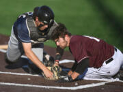 Pickles catcher Michael Campanga, left, tags out Raptors baserunner Austin Caviness at home plate Tuesday, June 28, 2022, during a game between the Ridgefield Raptors and the Portland Pickles at the Ridgefield Outdoor Recreation Complex.