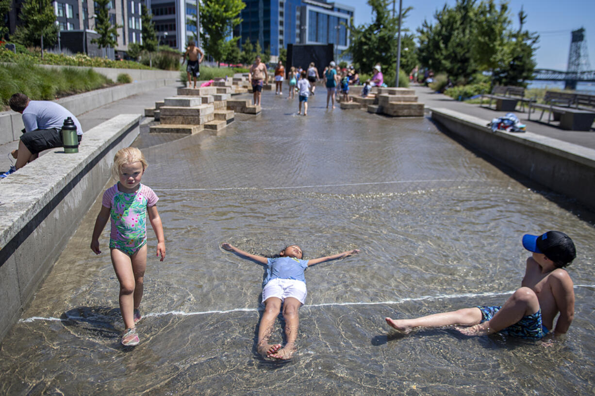 Vancouver kids Addy Bugge, 3, from left, joins Elizabeth White Eyes, 7, and Kai Sabanovic, 6, to beat the heat in the water feature at The Waterfront Vancouver on Monday afternoon. Forecasters predict cooler weather on the way.