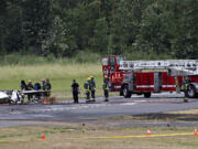 Officials look over the wreckage after a fatal plane crash at Pearson Field Airport on Tuesday morning, June 28, 2022.