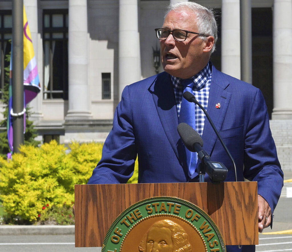 Washington state Gov. Jay Inslee addresses a gathering before raising the LGBTQ Pride Celebration flag seen behind him during a noon ceremony at the Capitol Campus flag circle, Tuesday, June 21, 2022, in Olympia, Wash. A variety of events celebrating the LGBTQ community statewide have taken place and are also scheduled through the month of June.