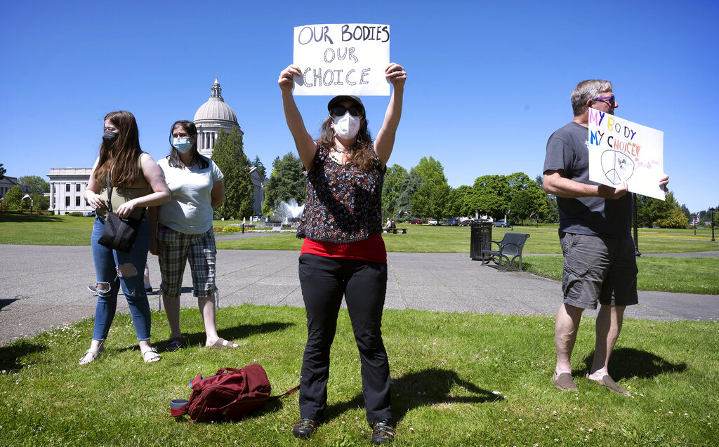 Women's rights supporters, from left, Lacy Nadeau, Carolyn Nadeau, Rebecca Rutzick and Joe Ward, all of Olympia, Wash., rally on the Capitol Campus in Olympia, Wash., Friday, June 24, 2022, following the morning's announcement of the U.S. Supreme Court's overturning of Roe v Wade.