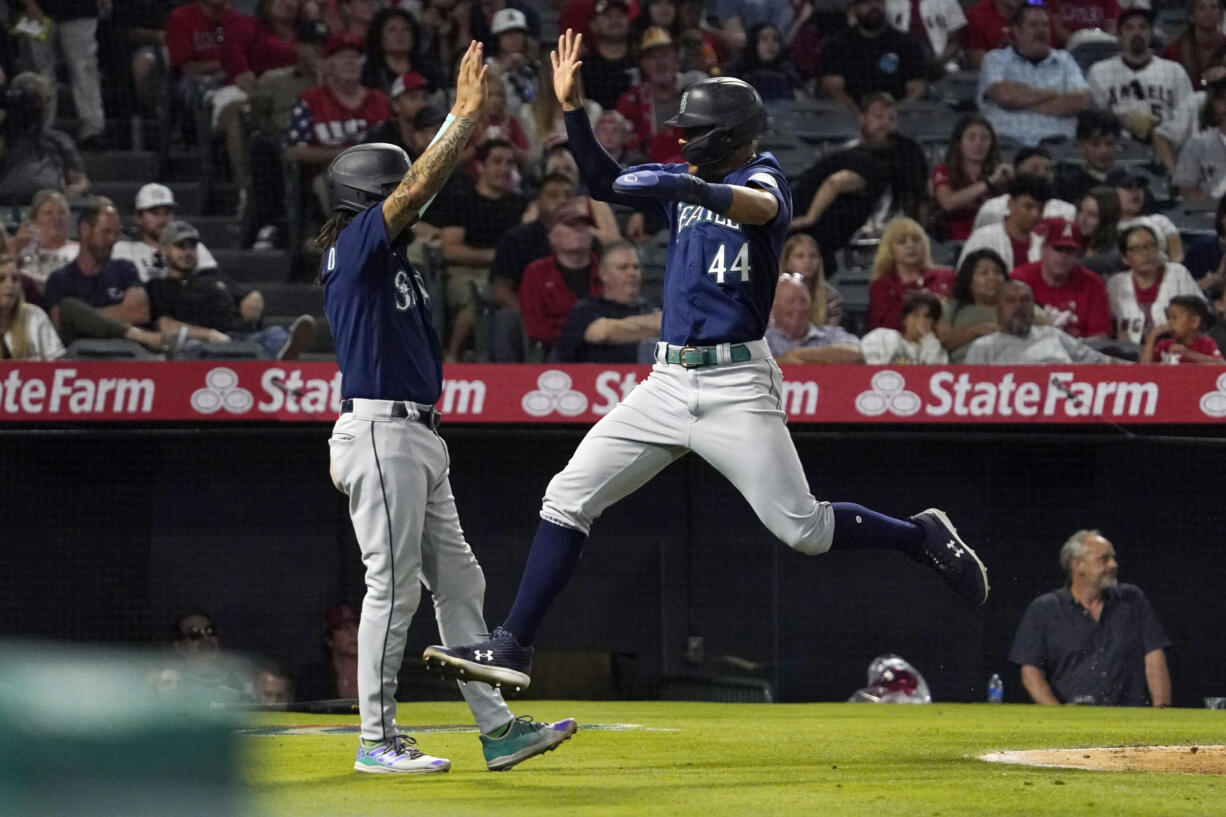 Seattle Mariners' Julio Rodriguez, right, celebrates with J.P. Crawford after they scored on a single by Kevin Padlo during the sixth inning of a baseball game Saturday, June 25, 2022, in Anaheim, Calif. (AP Photo/Mark J.