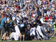 Mississippi's Jack Washburn, right, leaps on top of the team pile in celebration of their 4-2 victory over Oklahoma in Game 2 of the NCAA College World Series baseball finals, Sunday, June 26, 2022, in Omaha, Neb. Mississippi defeated Oklahoma 4-2 to win the championship. (AP Photo/Rebecca S.