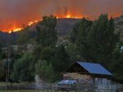 Flames and smoke rise on a ridge line above a ranch on Twisp River Road in Twisp, Wash., Wednesday, Aug. 19, 2015. Authorities on Wednesday afternoon urged people in the north-central Washington town to evacuate because of a fast-moving wildfire. (AP Photo/Ted S.