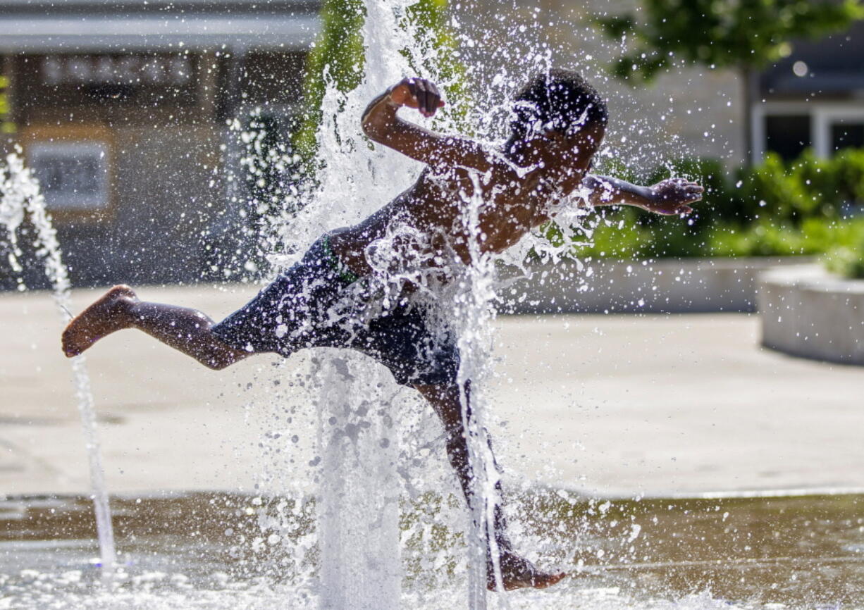 Damian Stewart, 8, plays in the splash pad at Howard Park, Tuesday, June 14, 2022, in downtown South Bend, Ind.