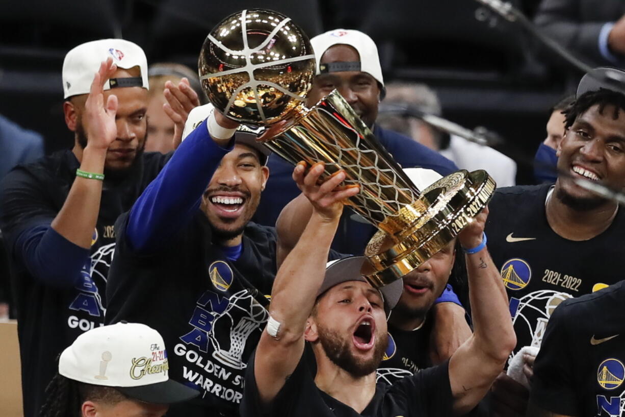 Golden State Warriors guard Stephen Curry, center, holds up the Larry O'Brien Championship Trophy with teammates after defeating the Boston Celtics in Game 6 of basketball's NBA Finals, Thursday, June 16, 2022, in Boston.