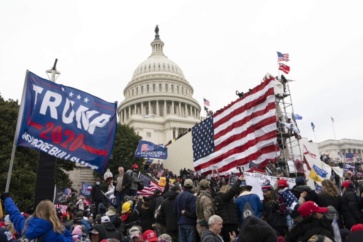 FILE - Rioters stand outside the U.S. Capitol in Washington, on Jan. 6, 2021.  A new poll shows that about half of Americans say former President Donald Trump should be charged with a crime for his role in what happened on Jan. 6. The Associated Press-NORC Center for Public Affairs Research poll found that 48% of U.S.