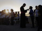 FILE - Migrants watching Pope Francis' Mass in Juarez, Mexico, from a levee along the banks of the Rio Grande in El Paso, Texas, take part in Communion, Wednesday, Feb. 17, 2016. According to a poll from The Associated Press-NORC Center for Public Affairs Research conducted in mid-May 2022, only 31% of lay Catholics agree that politicians supporting abortion rights should be denied Communion, while 66% say they be allowed access to the sacrament.