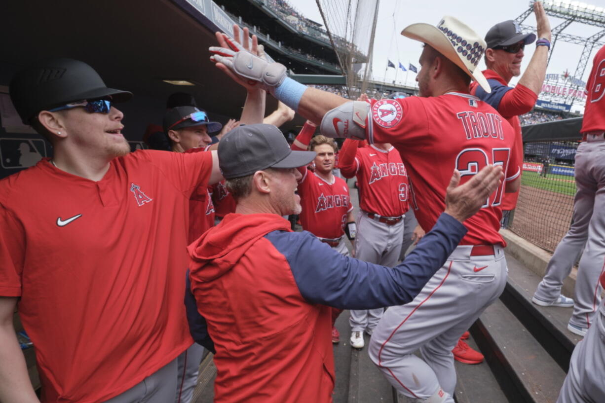 Los Angeles Angels' Mike Trout, right, is greeted in the dugout after hitting a two-run home run on a pitch from Seattle Mariners starting pitcher Logan Gilbert during the fourth inning of a baseball game, Sunday, June 19, 2022, in Seattle.