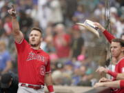 Los Angeles Angels' Mike Trout, left, points toward the outfield as he is greeted at the dugout after hitting a two-run home run in the tenth inning of the first baseball game of a doubleheader against the Seattle Mariners, Saturday, June 18, 2022, in Seattle. The Angels won 4-2 in ten innings. (AP Photo/Ted S.