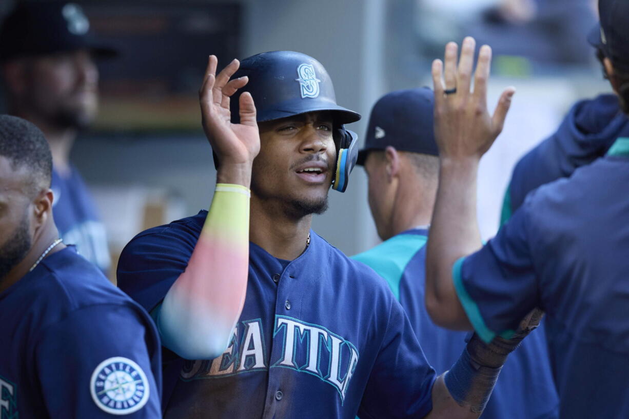 Seattle Mariners' Julio Rodriguez is greeted in the dugout after scoring on a sacrifice hit by Abraham Toro against the Oakland Athletics during first inning of a baseball game, Thursday, June 30, 2022, in Seattle.