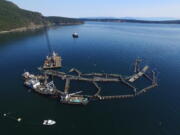 FILE - In this photo provided by the Washington State Department of Natural Resources, a crane and boats are anchored next to a collapsed "net pen" used by Cooke Aquaculture Pacific to farm Atlantic Salmon near Cypress Island in Washington state on Aug. 28, 2017, after a failure of the nets allowed tens of thousands of the nonnative fish to escape. A Washington state jury on Wednesday, June 22, 2022, awarded the Lummi Indian tribe $595,000 over the 2017 collapse of the net pen where Atlantic salmon were being raised, an event that elicited fears of damage to wild salmon runs and prompted the Legislature to ban the farming of the nonnative fish.