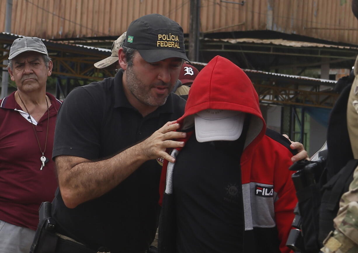 A federal police officer escorts a suspect towards a river in the area where Indigenous expert Bruno Pereira and freelance British journalist Dom Phillips disappeared, in Atalaia do Norte, Amazonas state, Brazil, Wednesday, June 15, 2022. Federal police said in a statement Tuesday night that they had arrested a second suspect in connection with the disappearance of Phillips and Pereira in a remote area of the Amazon.