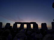 Dawn breaks behind the stones during the Summer Solstice festivities at Stonehenge in Wiltshire, England, Tuesday, June 21, 2022. After two years of closure due to the COVID-19 pandemic, Stonehenge reopened Monday for the Summer Solstice celebrations.