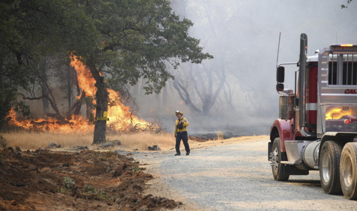 A firefighter assesses the approaching fire along Troost Trail in California's rural Nevada County as the Rices Fire burned more than 300 acres, Tuesday, June 28, 2022.