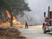 A firefighter assesses the approaching fire along Troost Trail in California's rural Nevada County as the Rices Fire burned more than 300 acres, Tuesday, June 28, 2022.