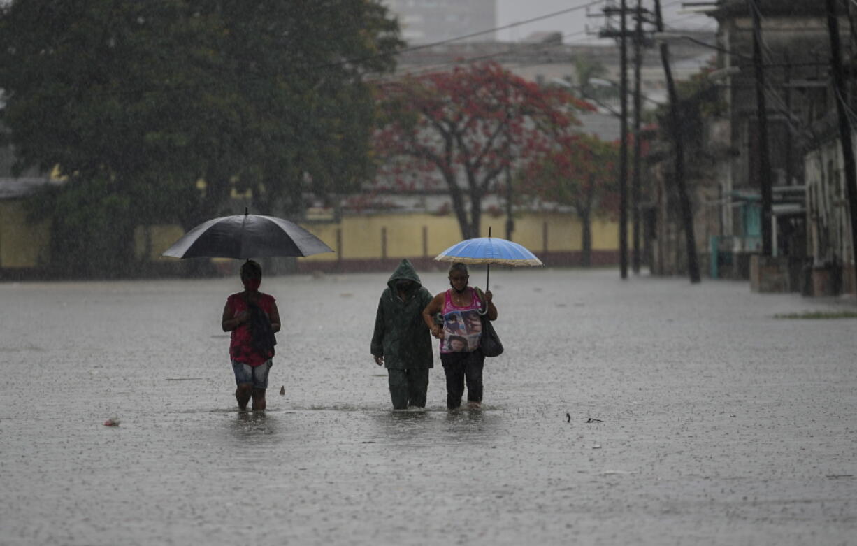 Residents wade through a street flooded by heavy rains, in Havana, Cuba, Friday, June 3, 2022. Heavy rains have drenched Cuba with almost non-stop rain for the last 24 hours as tropical storm watches were posted Thursday for Florida, Cuba and the Bahamas as the system that battered Mexico moves to the east.